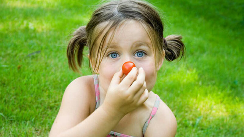 Mädchen hält sich Tomate vor die Nase