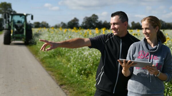 Landwirtin und Landwirt stehen an einem Feldweg